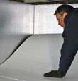 A contractor installing TerraBlock™ floor insulation in a Newark crawl space
